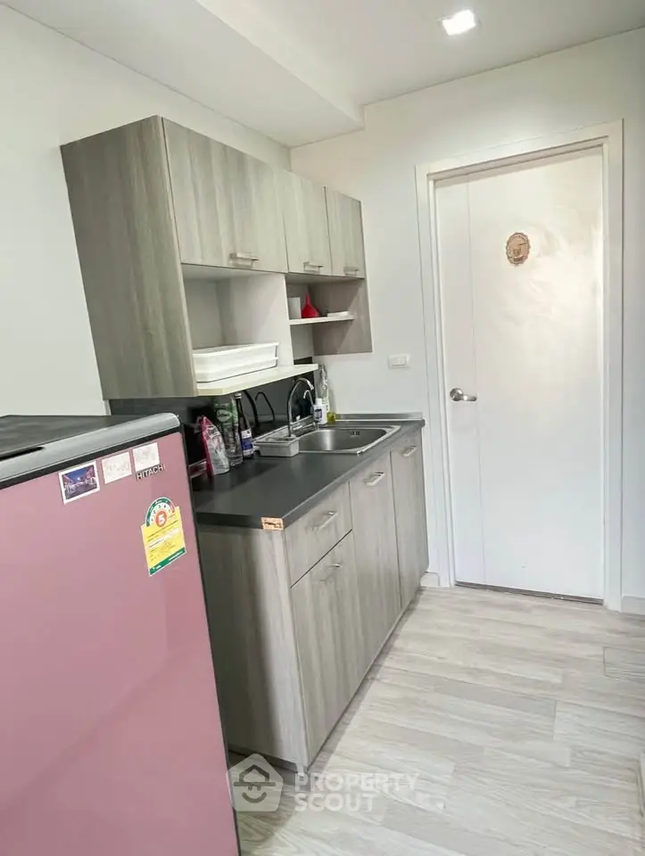 Modern kitchen with sleek cabinetry and compact fridge in a cozy apartment setting.