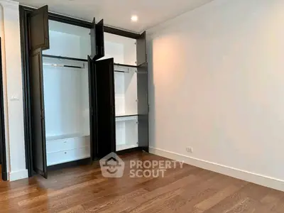 Spacious empty room with open closet and wooden flooring