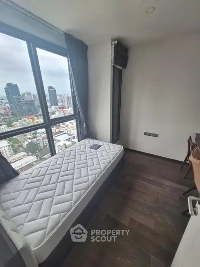 Modern bedroom with city view, featuring a single bed and floor-to-ceiling windows in a high-rise apartment.