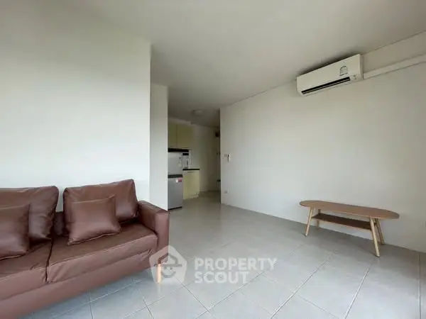 Spacious living room with modern sofa and air conditioning, perfect for relaxation.