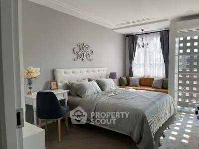 Elegant bedroom with stylish decor and natural light, featuring a cozy seating area by the window.