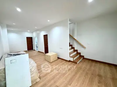 Spacious modern living area with wooden flooring and staircase, ideal for contemporary living.
