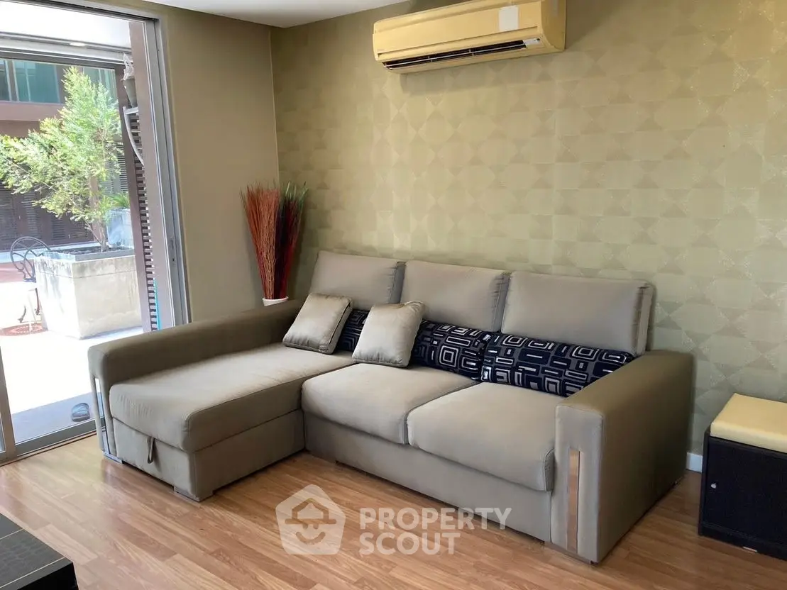 Modern living room with stylish sofa and air conditioning, featuring a cozy ambiance and wooden flooring.