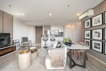 Modern open-plan living room with stylish decor and dining area, featuring contemporary furniture.