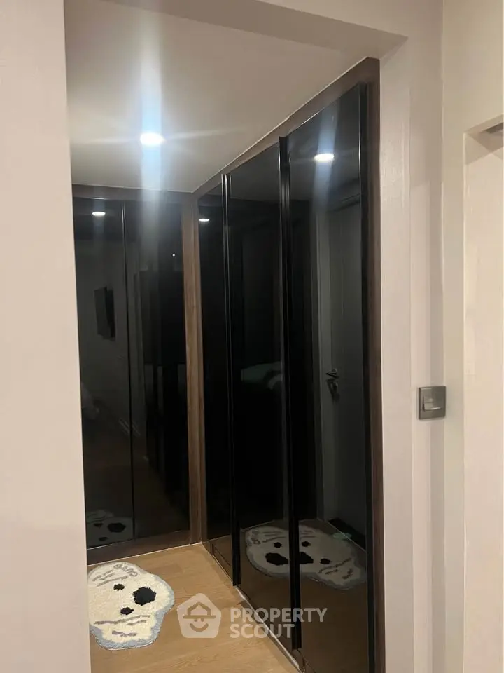 Modern hallway with sleek black mirrored closets and wooden flooring