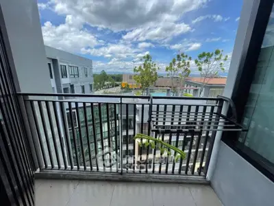 Modern balcony with sleek railing offering a stunning view of contemporary architecture and lush greenery.