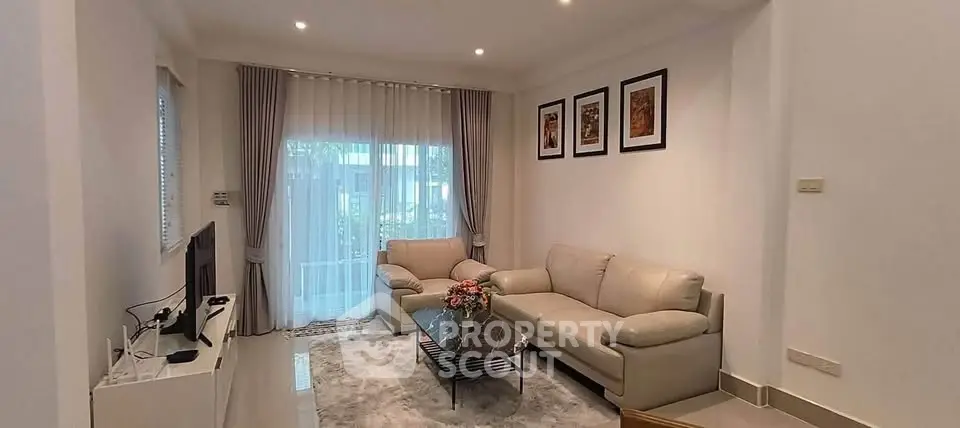 Elegant living room with modern decor, cozy seating, and natural light from large windows.