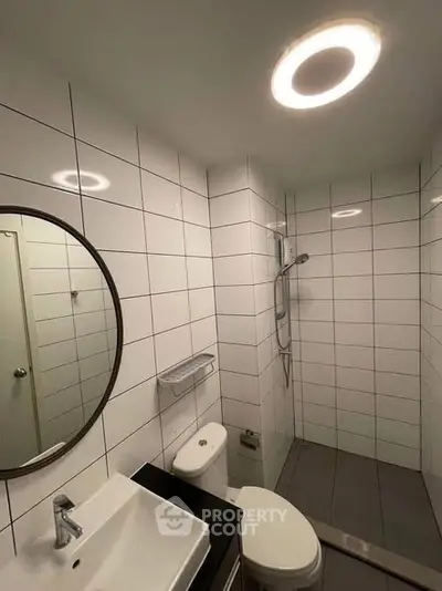 Modern bathroom with sleek white tiles and circular mirror
