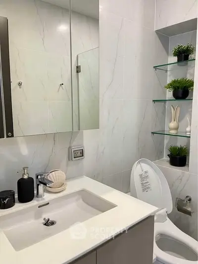 Modern bathroom with sleek white fixtures and decorative shelving.