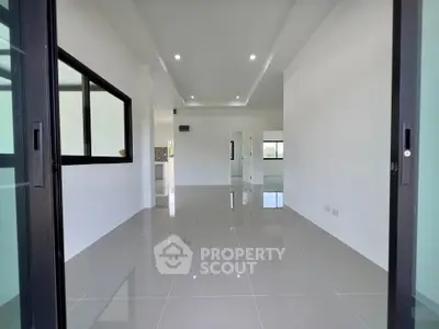 Spacious modern living room with glossy tile flooring and large windows.
