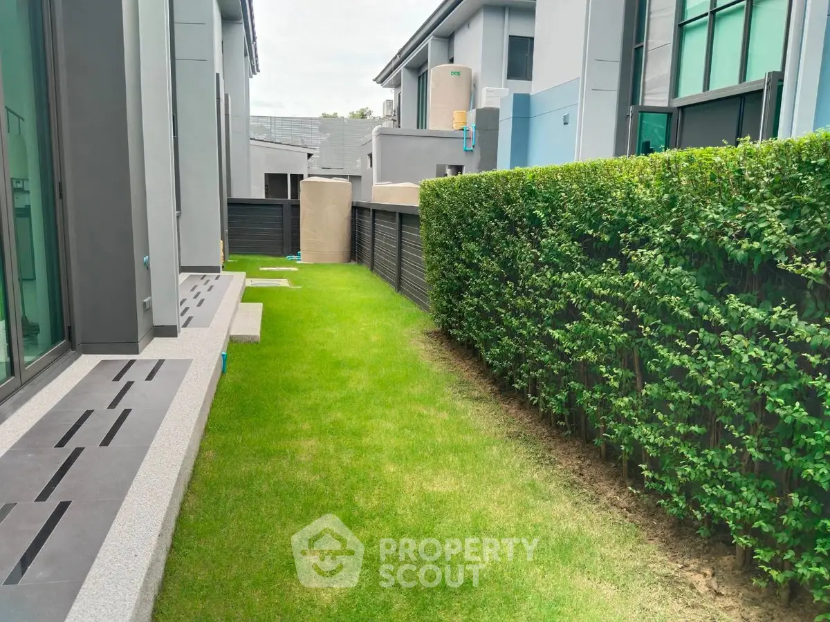 Modern townhouse exterior with lush green lawn and privacy hedge