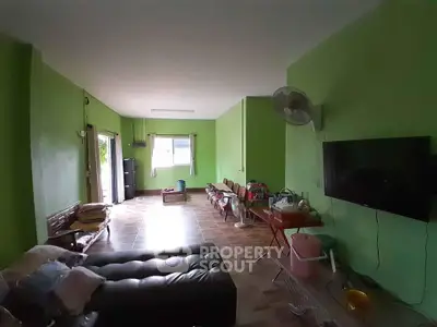 Spacious living room with green walls, TV, and comfortable seating, perfect for relaxation.