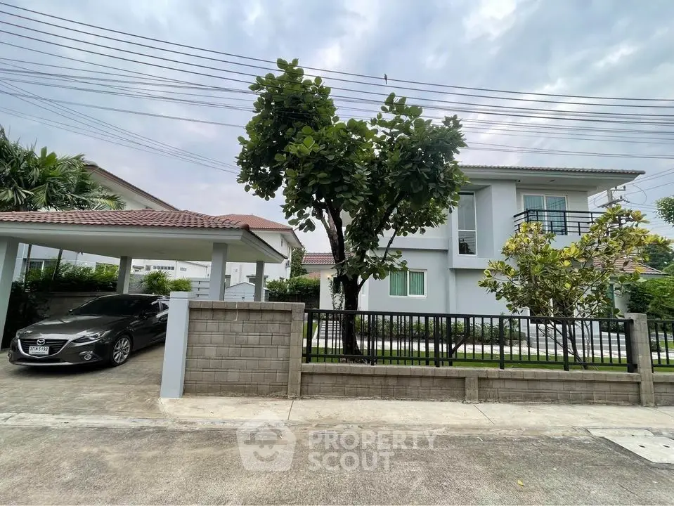 Modern two-story house with carport and lush garden in a serene neighborhood.