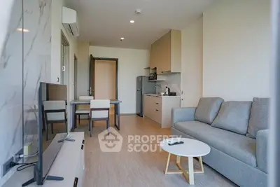Modern living room with open kitchen, stylish furniture, and natural light.