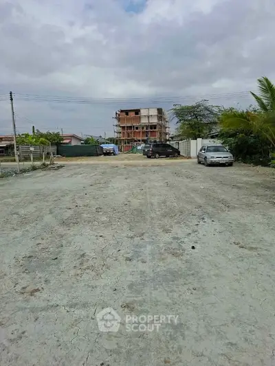 Spacious open lot with distant view of a building under construction, ideal for development.