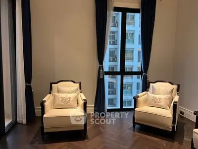 Elegant living room with two armchairs and large window offering city view