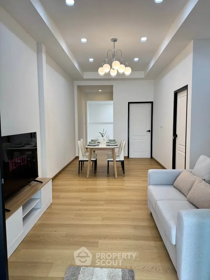 Modern living room with dining area, stylish lighting, and cozy sofa in a contemporary apartment.