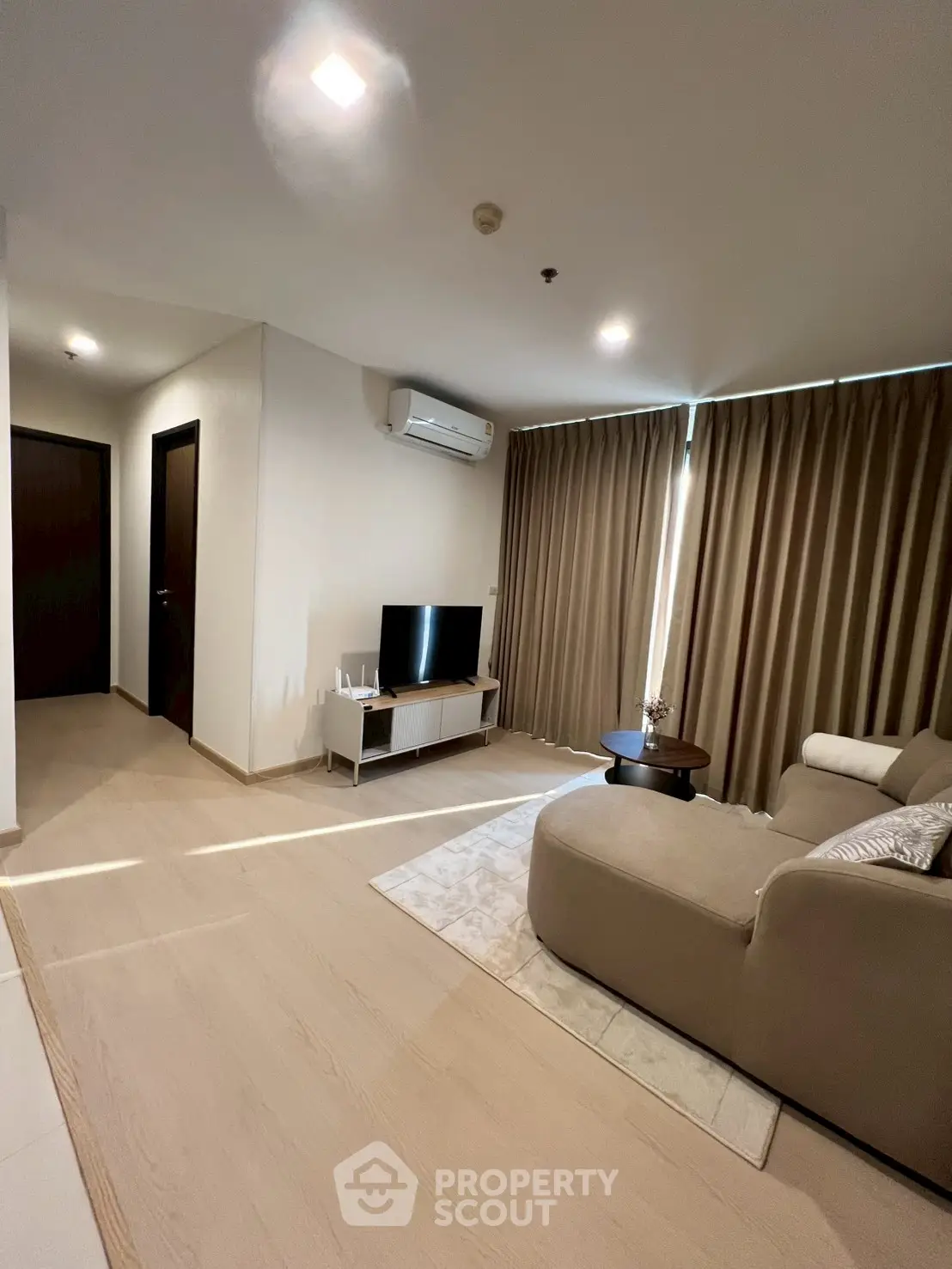 Modern living room with cozy sofa, flat-screen TV, and elegant curtains in a stylish apartment.
