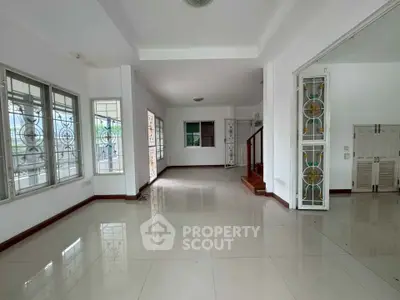 Spacious open-plan living area with large windows and elegant staircase