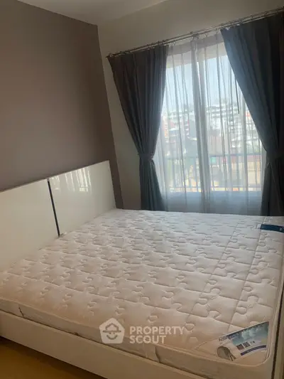 Spacious bedroom with large window and natural light in modern apartment.