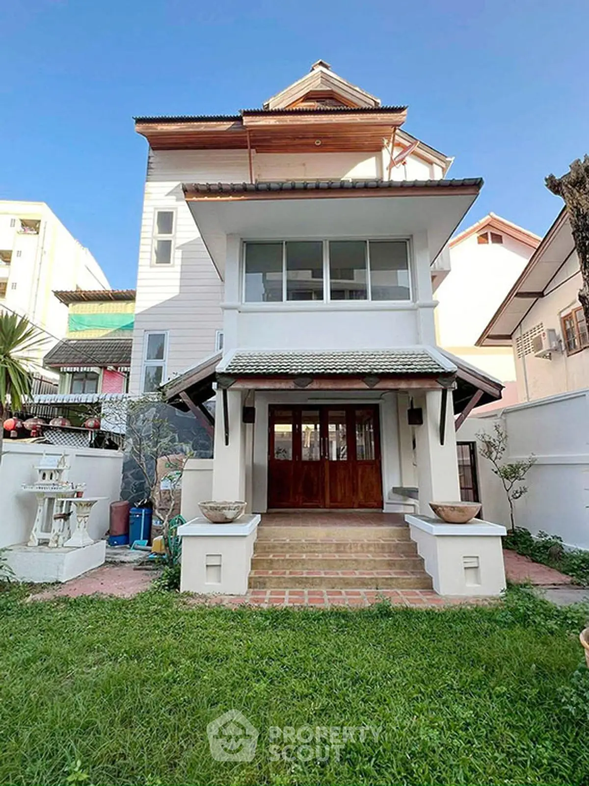 Charming multi-story house with traditional architecture and lush green lawn in a serene neighborhood.