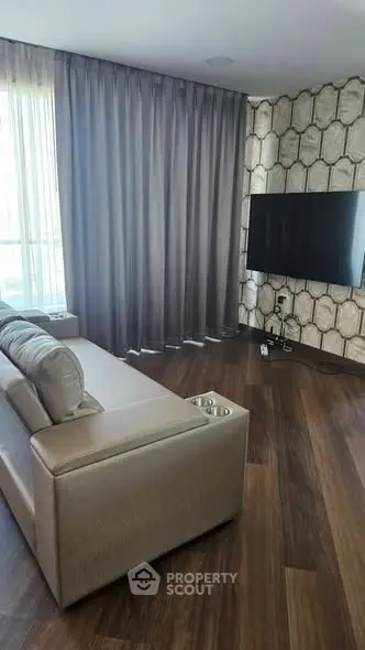 Modern living room with sleek sofa and wall-mounted TV, featuring elegant wood flooring and stylish curtains.