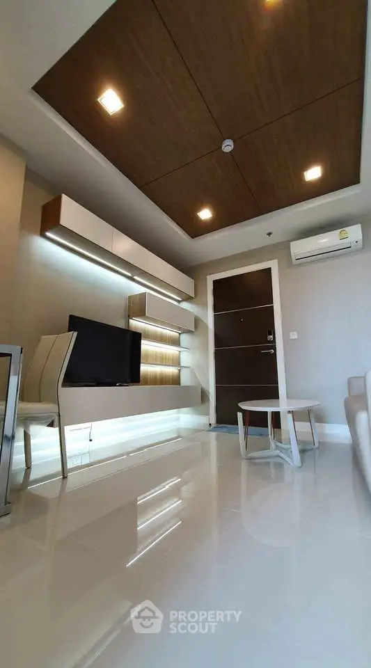 Modern living room with sleek furniture and ambient lighting, featuring a wall-mounted TV and stylish ceiling design.
