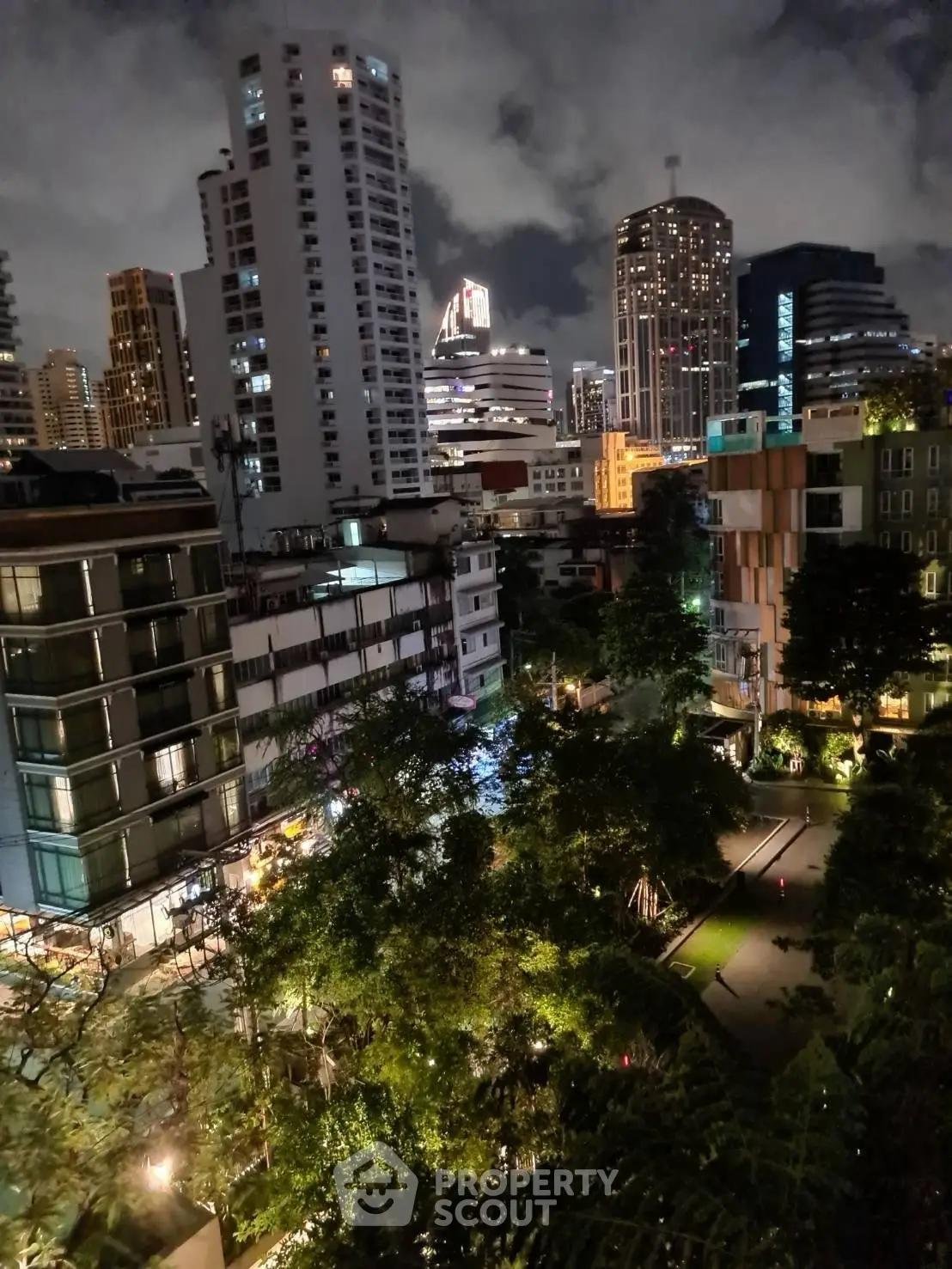 Stunning cityscape view from a high-rise balcony at night, showcasing vibrant urban lights.