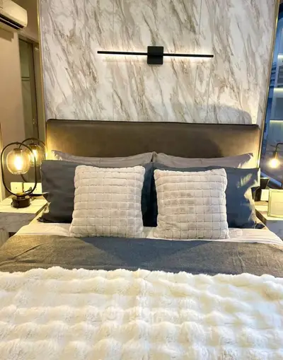 Luxurious bedroom with elegant lighting and plush bedding in modern apartment.
