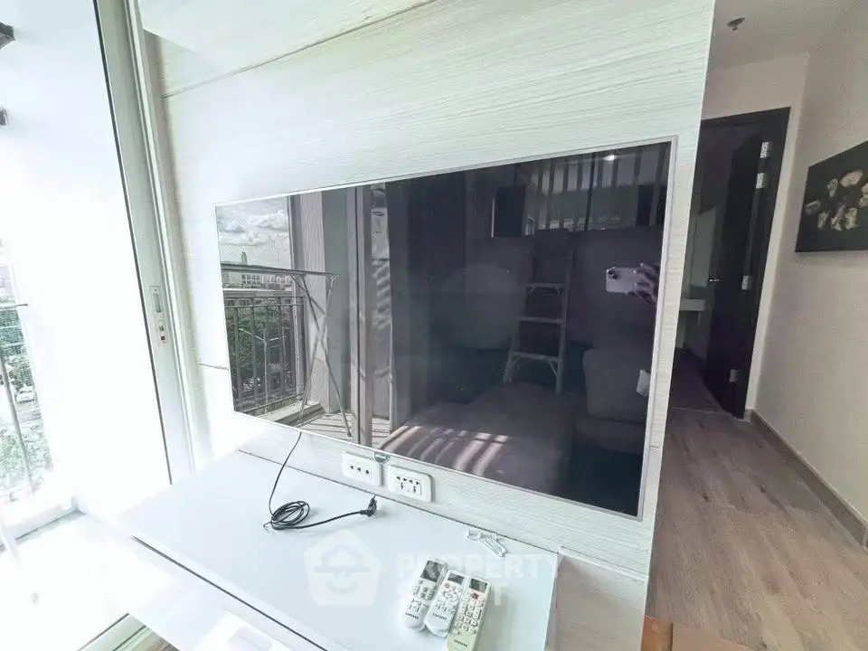 Modern living room with wall-mounted TV and balcony view in stylish apartment.