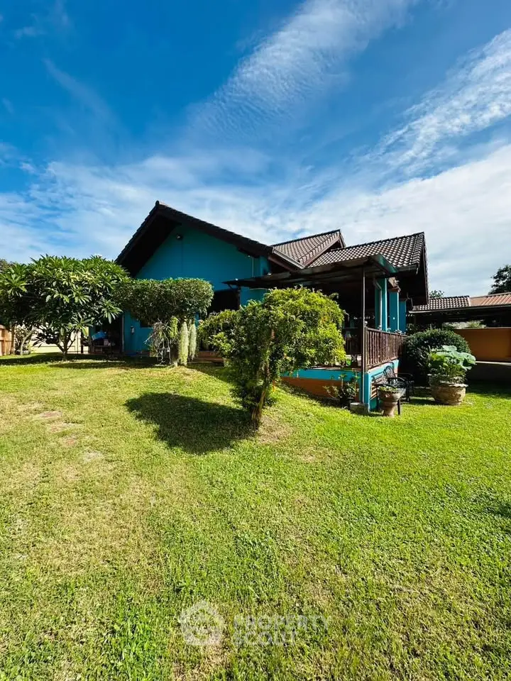 Charming suburban home with lush garden and spacious lawn under a clear blue sky.