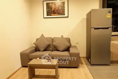 Cozy living room with modern sofa and sleek refrigerator, perfect for urban living.