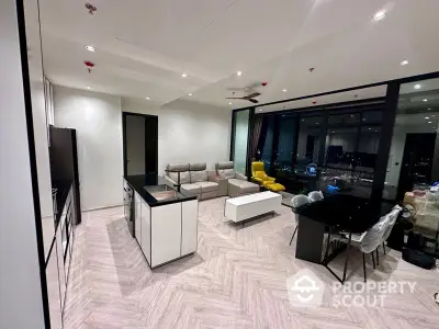 Spacious modern living room with herringbone floor pattern, sleek furniture, and panoramic city view through floor-to-ceiling windows.