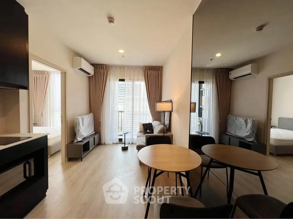 Modern living room with dining area and large windows in a stylish apartment.