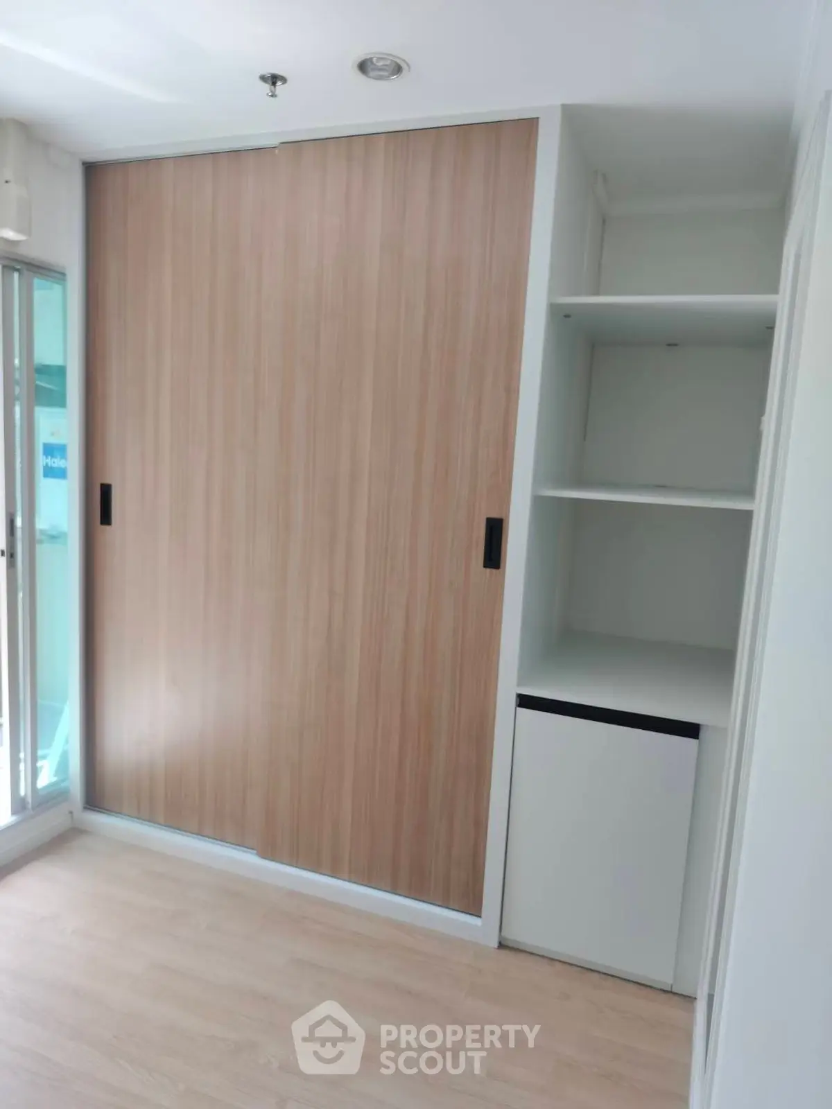 Modern storage space with sliding wooden doors and open shelves in a bright room.