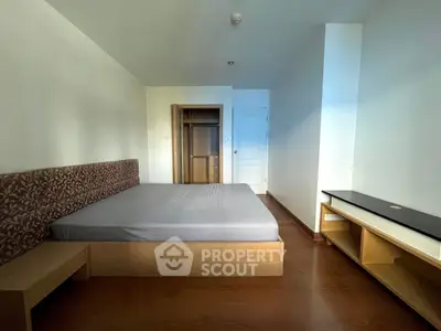 Spacious bedroom with wooden flooring and built-in wardrobe in modern apartment.