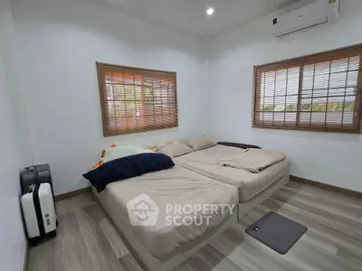 Cozy bedroom with twin beds, air conditioning, and wooden blinds for a comfortable living experience.