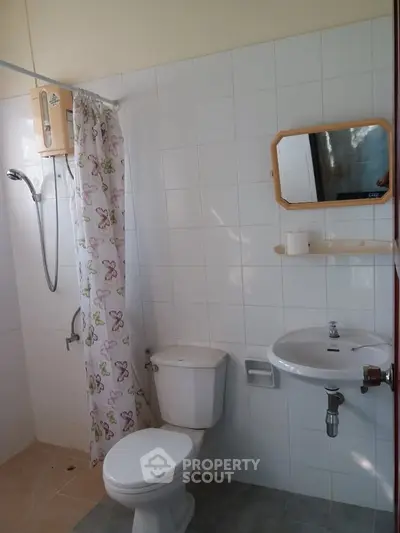 Cozy bathroom with shower, toilet, and sink in a tiled setting, perfect for a compact living space.