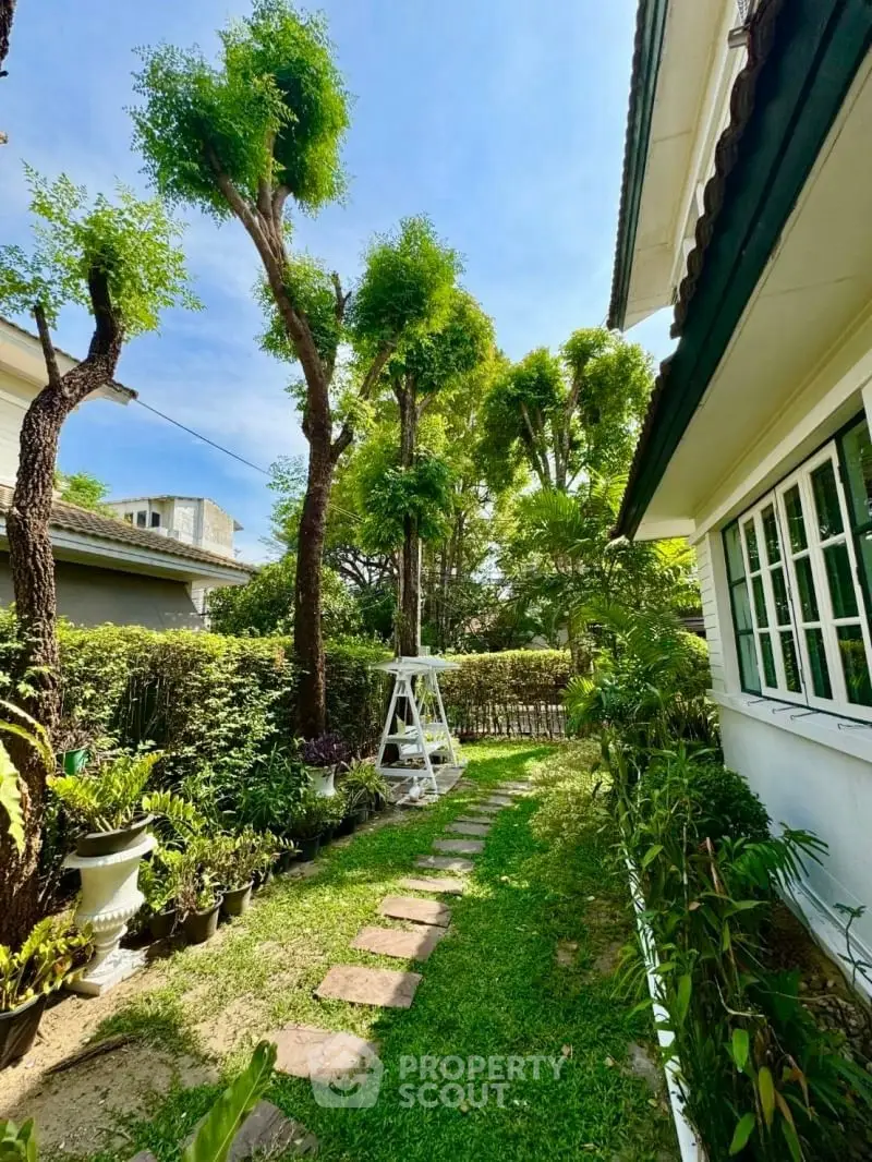 Charming garden view with lush greenery and pathway beside a cozy home.