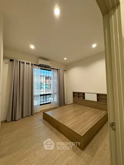 Spacious bedroom with wooden flooring and large window in modern apartment
