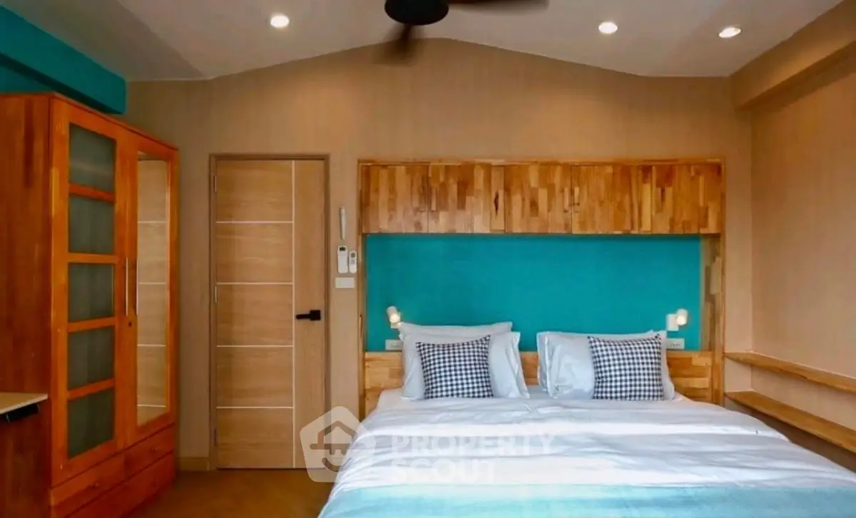 Modern bedroom with wooden accents and teal feature wall, showcasing cozy and stylish interior design.