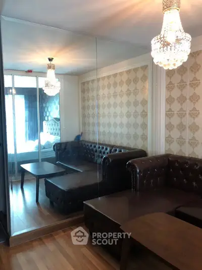 Luxurious living room with elegant chandeliers and leather sofas, featuring mirrored walls for a spacious feel.