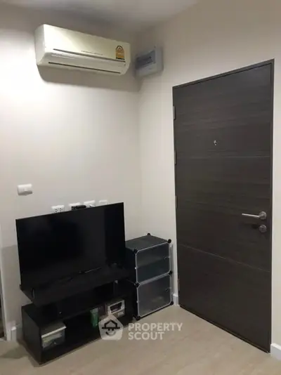Modern living room corner with TV and air conditioning unit, sleek door design.