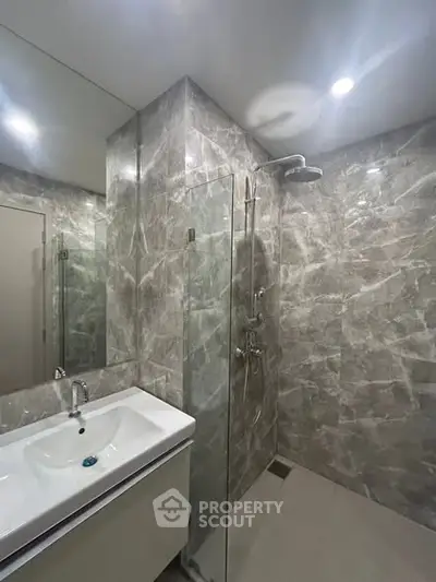 Modern bathroom with sleek marble tiles and glass shower enclosure