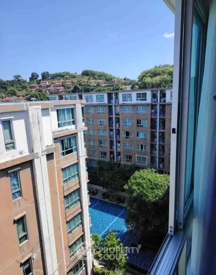 Stunning view from high-rise apartment overlooking pool and lush greenery.