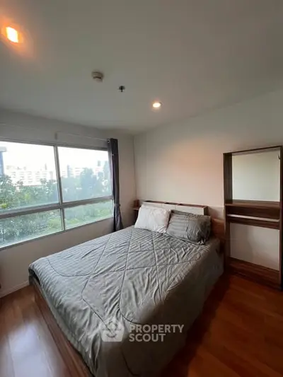 Cozy bedroom with large window offering a scenic view, featuring a comfortable bed and wooden flooring.