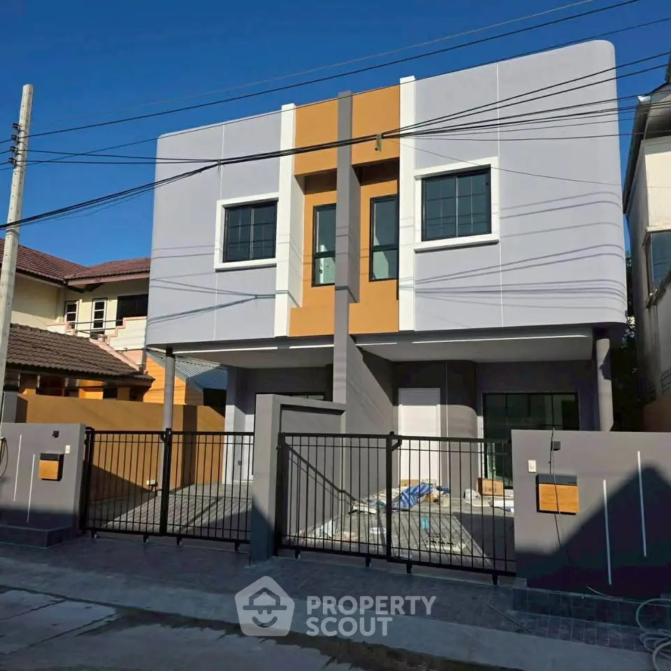 Modern two-story house with sleek design and gated entrance in a suburban neighborhood.