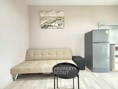 Modern living room with beige sofa, sleek refrigerator, and stylish decor in a cozy apartment.