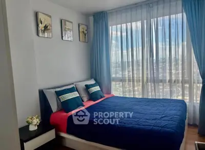 Modern bedroom with large window and stylish decor in a high-rise apartment.