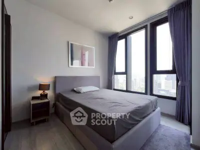 Modern bedroom with large windows and city view, featuring a stylish bed and elegant decor.